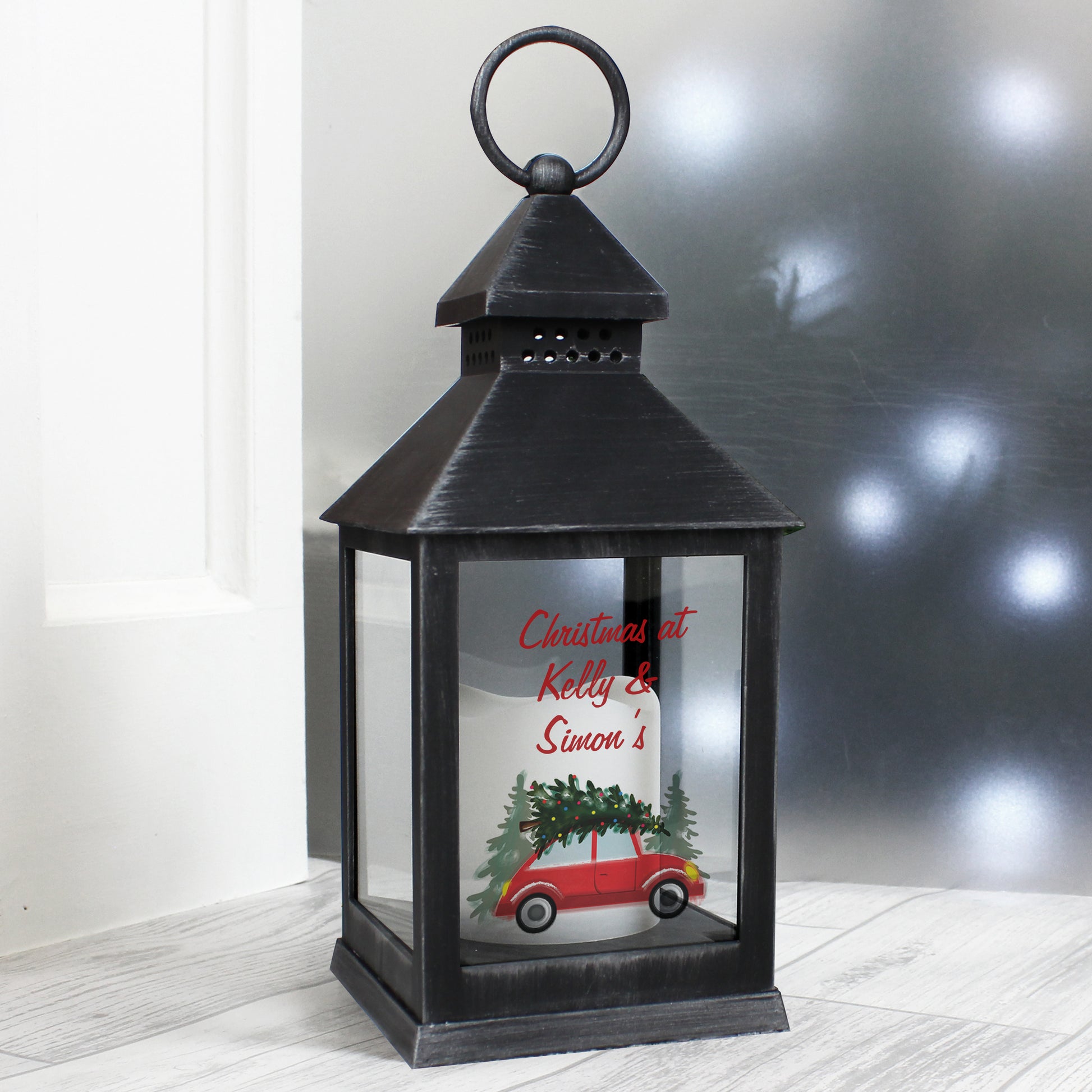 Black lantern with a decorative message inside on a light wooden floor.