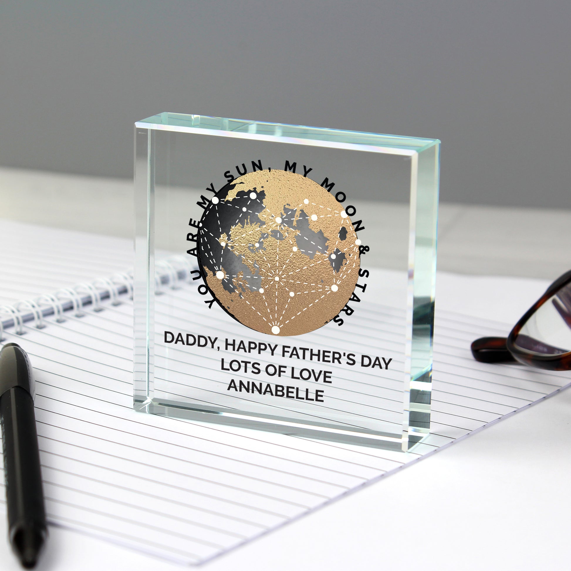 Personalised glass block with engraved message on a desk