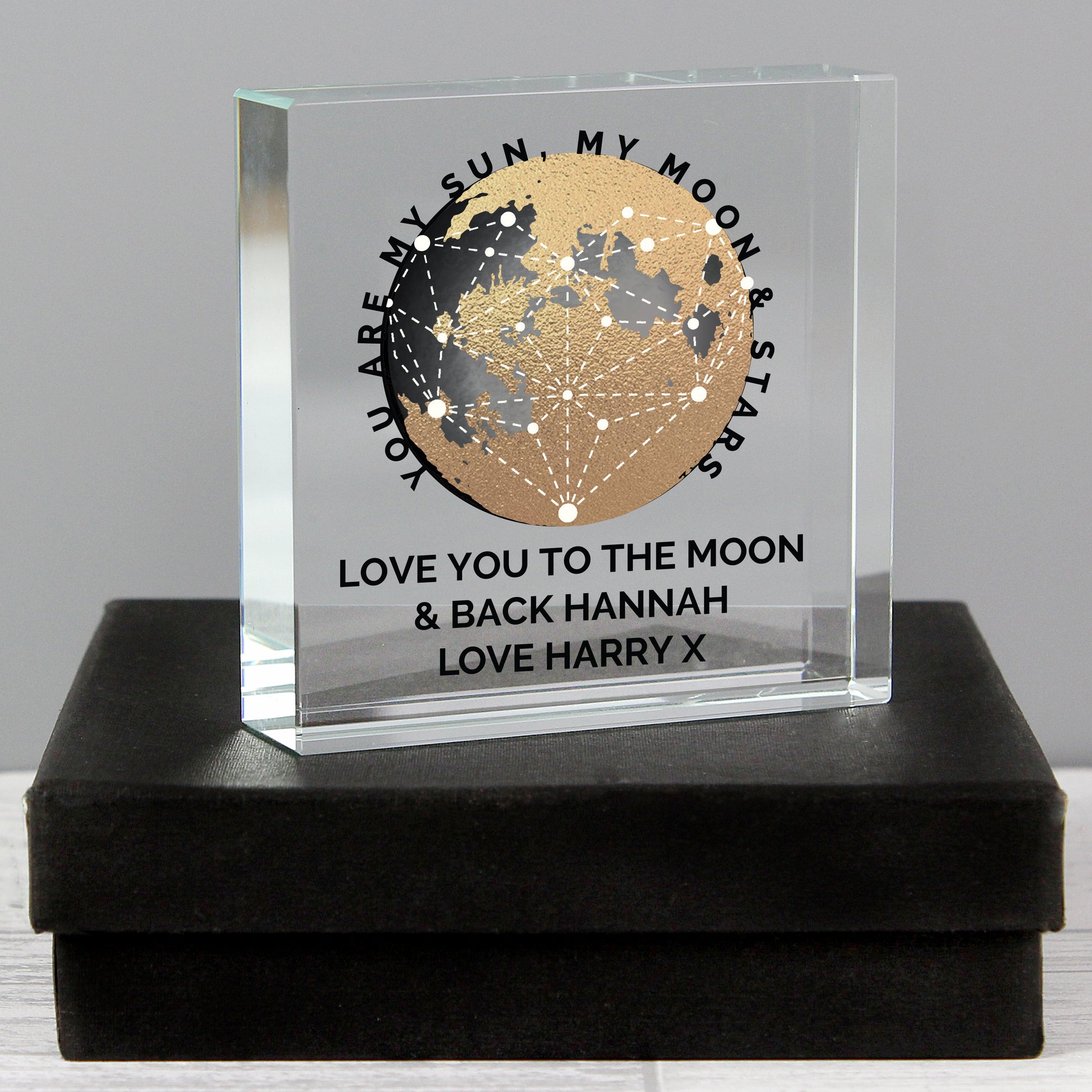 Personalised glass block with moon design and engraved text on a black box.