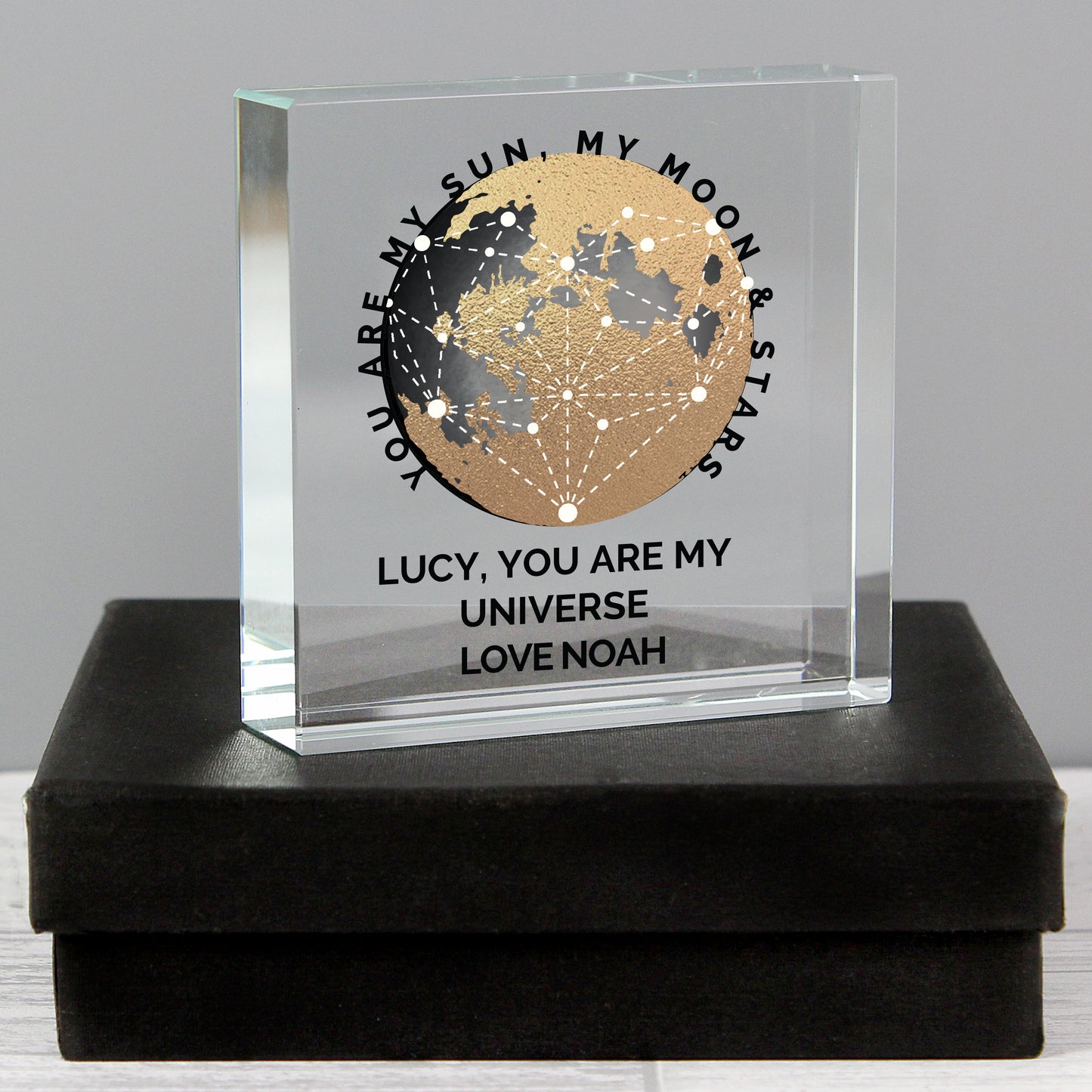 Clear glass block with celestial design and engraved text on a black box
