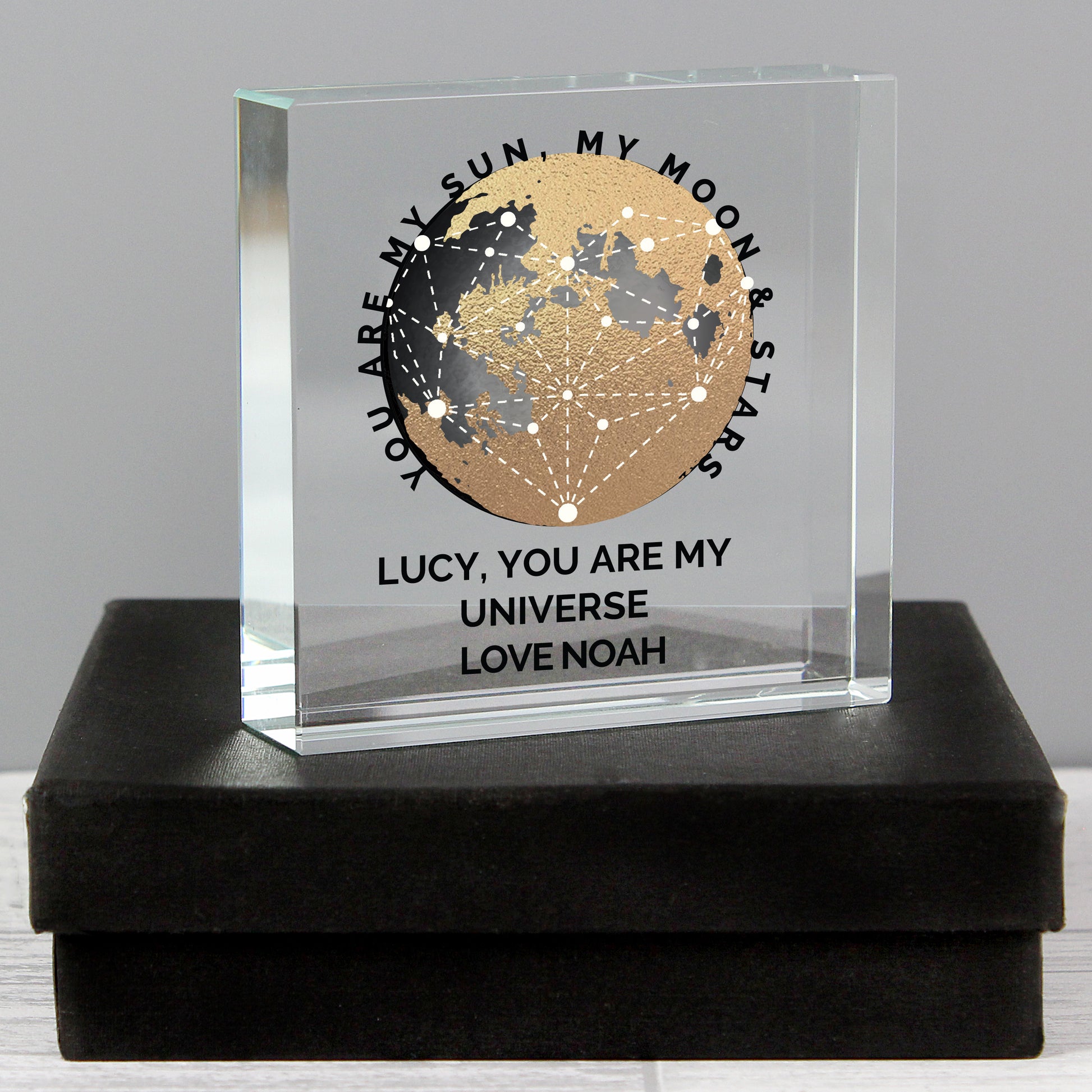 Clear glass block with celestial design and engraved text on a black box