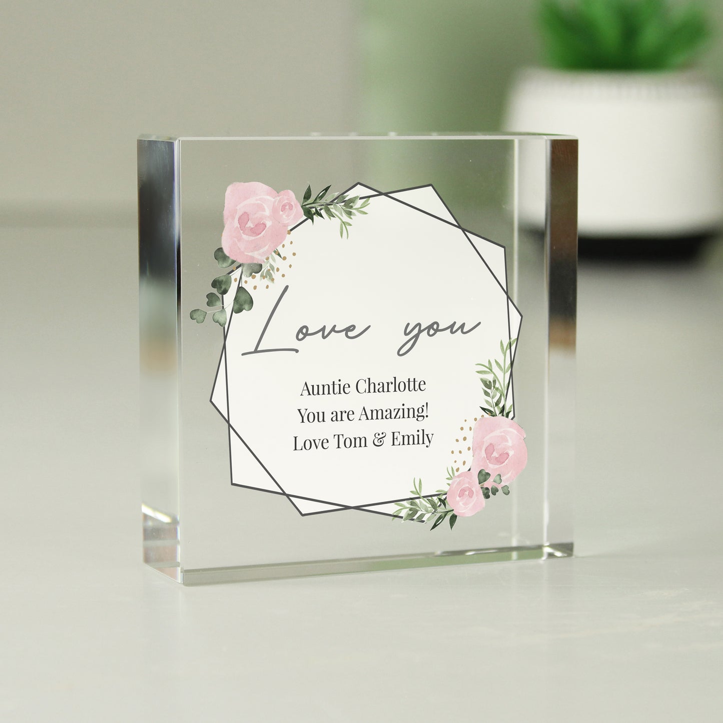 Clear glass block with floral design and text on a light background