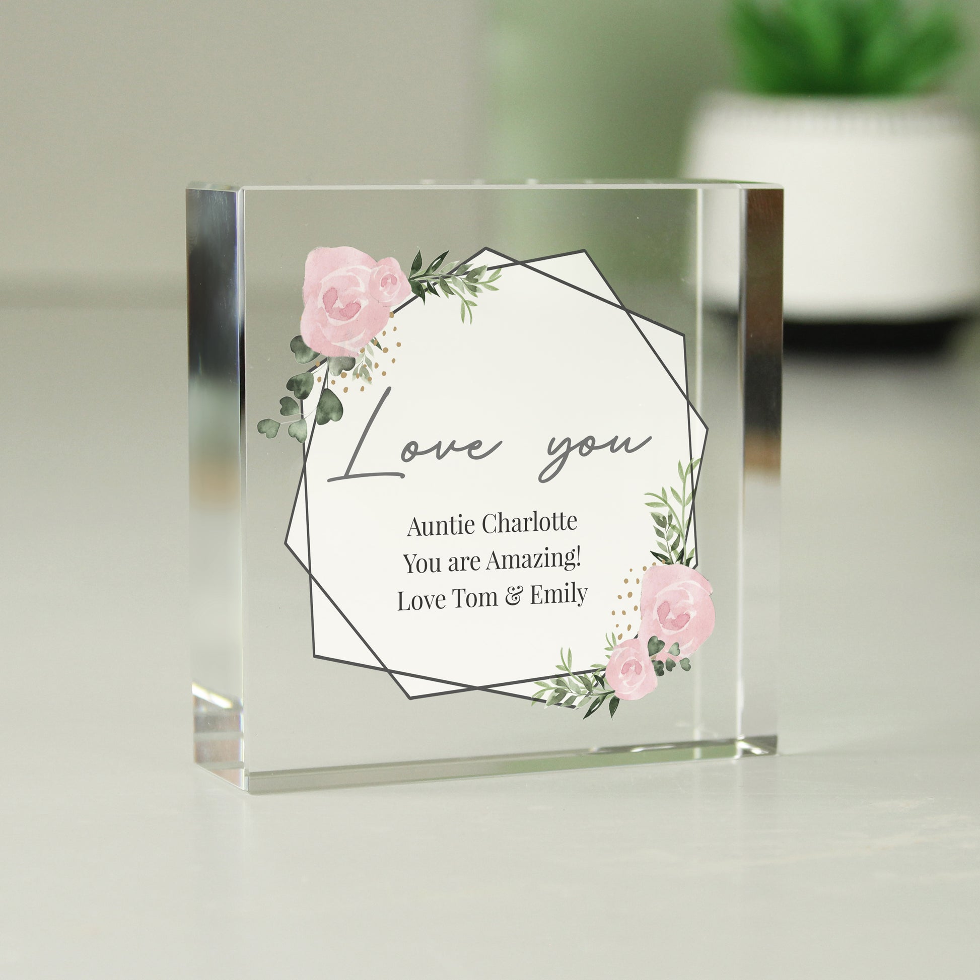 Clear glass block with floral design and text on a light background