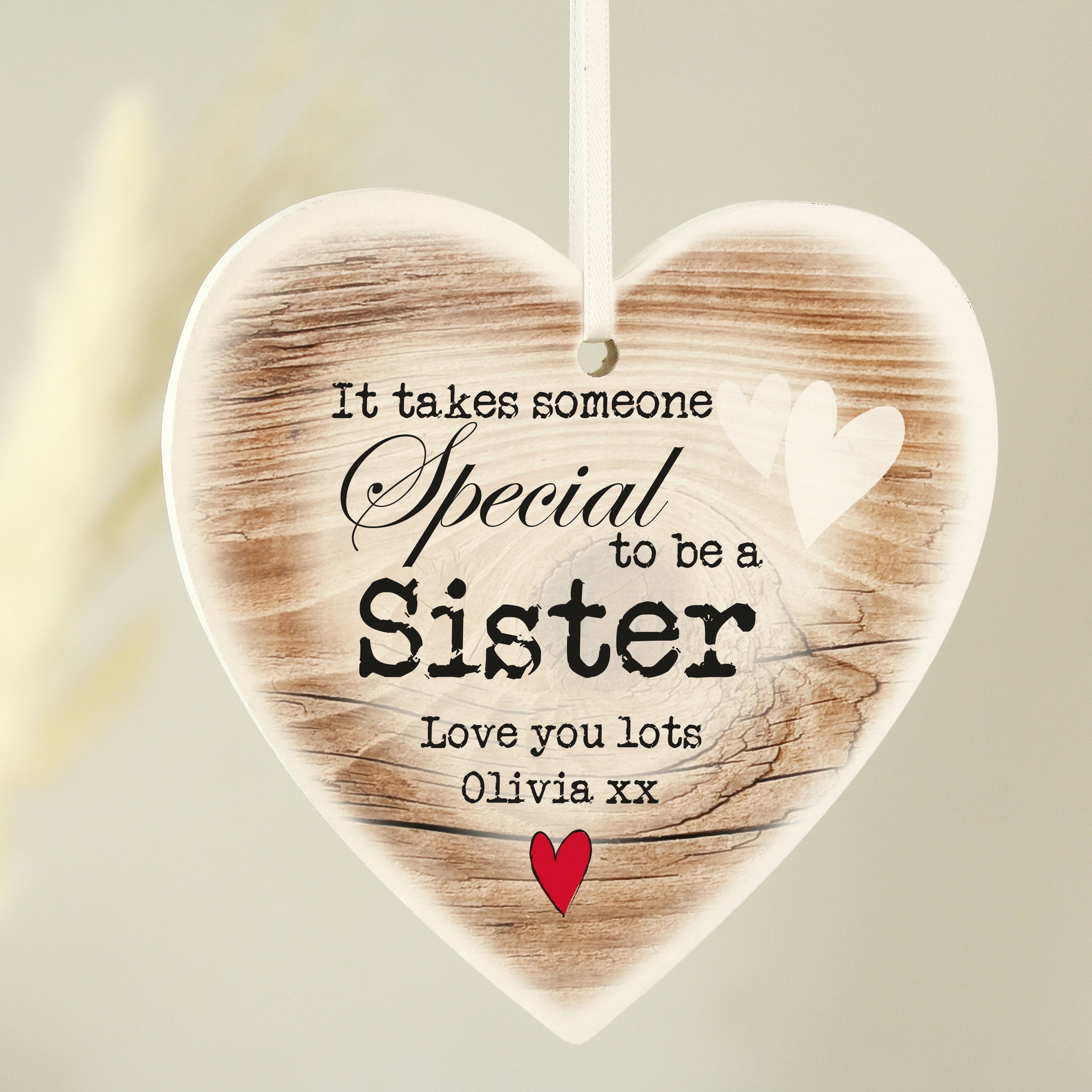 Heart-shaped wooden plaque with printed text and a red heart on a light background