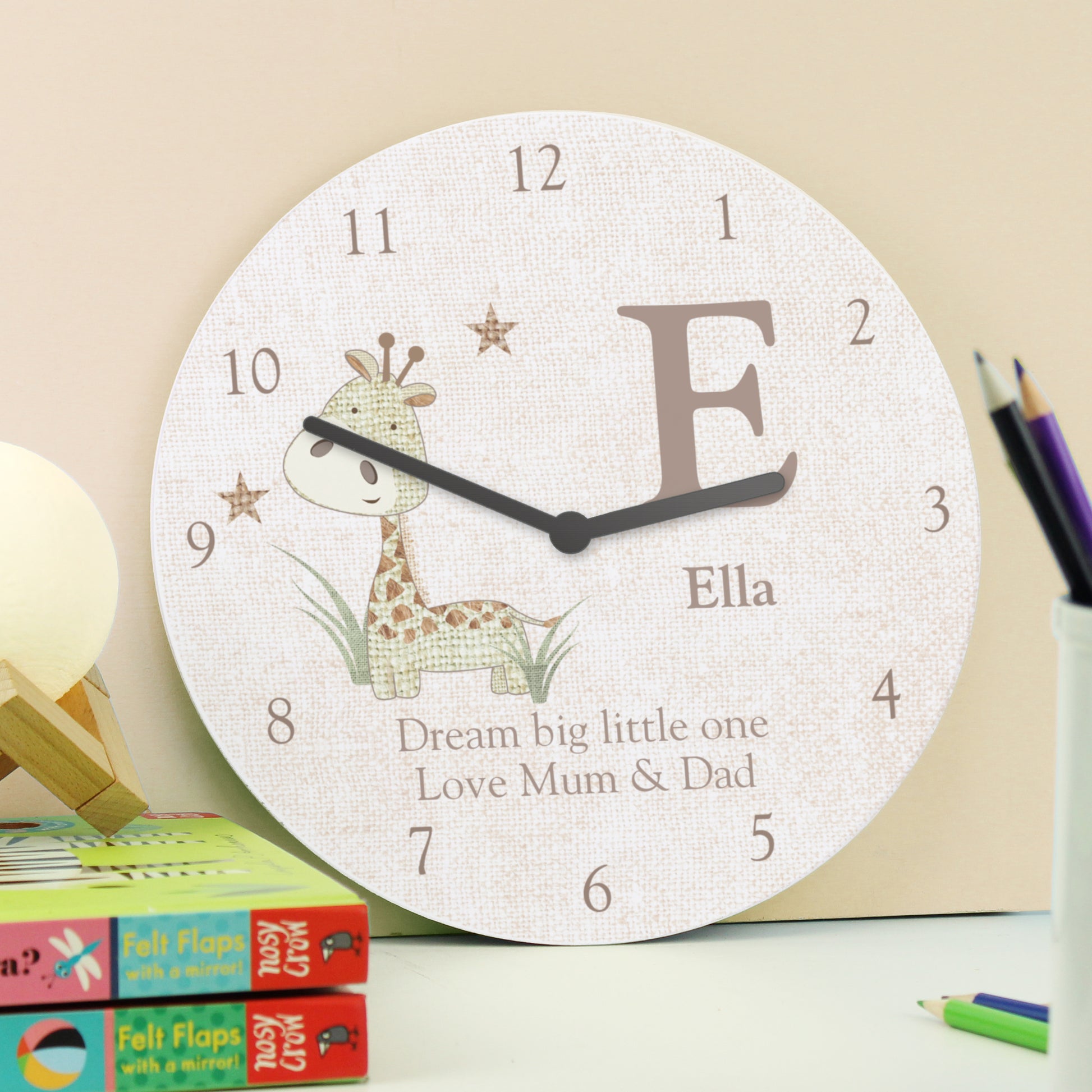 Children's wall clock with a giraffe design and personalised text on a desk.