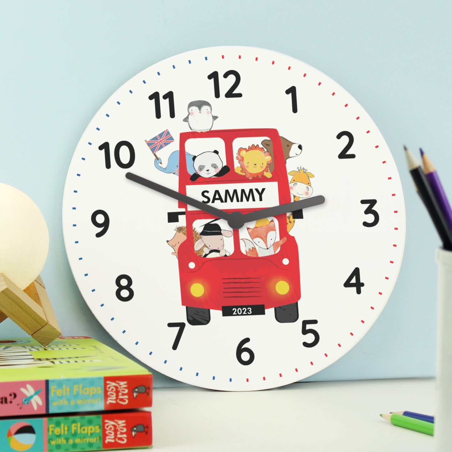 Children's wall clock with a red bus design and the name 'Sammy' on a light blue background.
