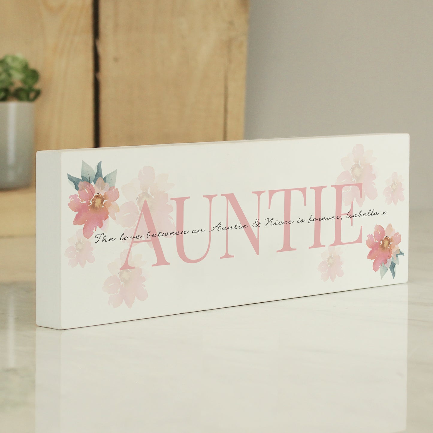 Decorative sign with 'Auntie' and floral designs on a neutral background