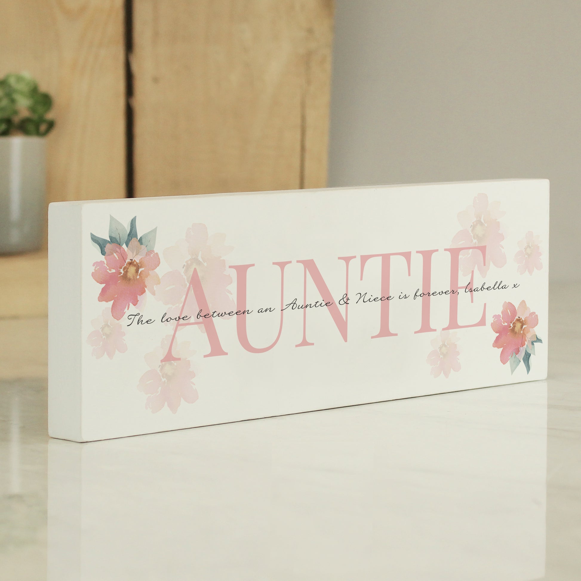 Decorative sign with 'Auntie' and floral designs on a neutral background