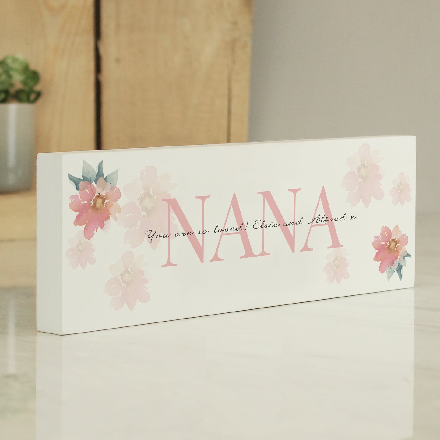 Decorative sign with 'NANA' and floral designs on a white background