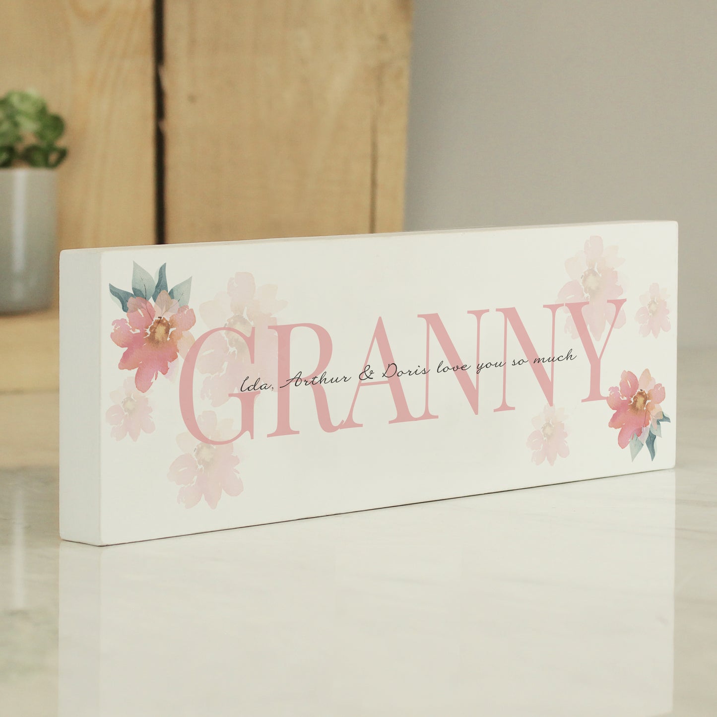 Decorative sign with 'GRANNY' and floral designs on a wooden surface.