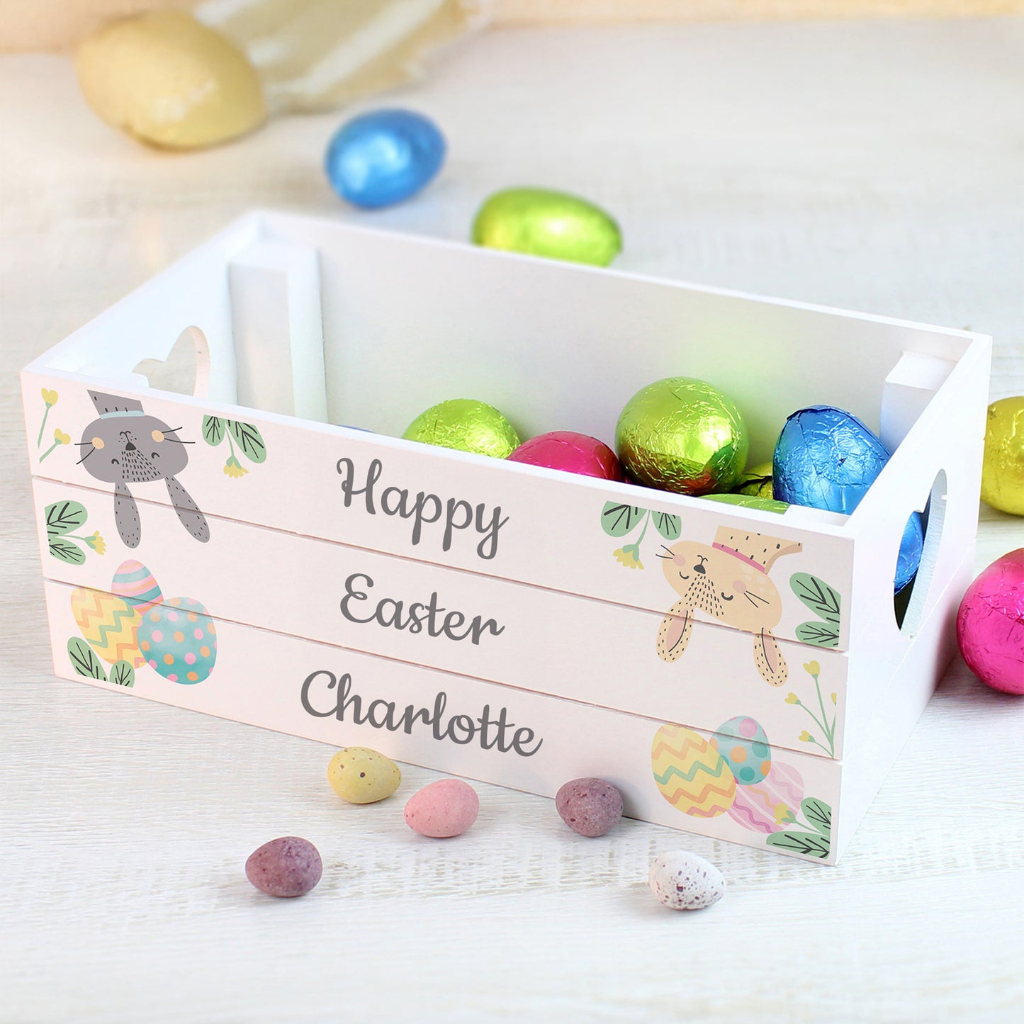 Easter basket with colorful eggs and personalized 'Happy Easter' sign on a light background