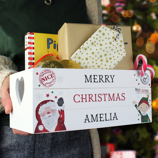 Gift box with 'Merry Christmas Amelia' text, surrounded by wrapped gifts, against a blurred festive background.
