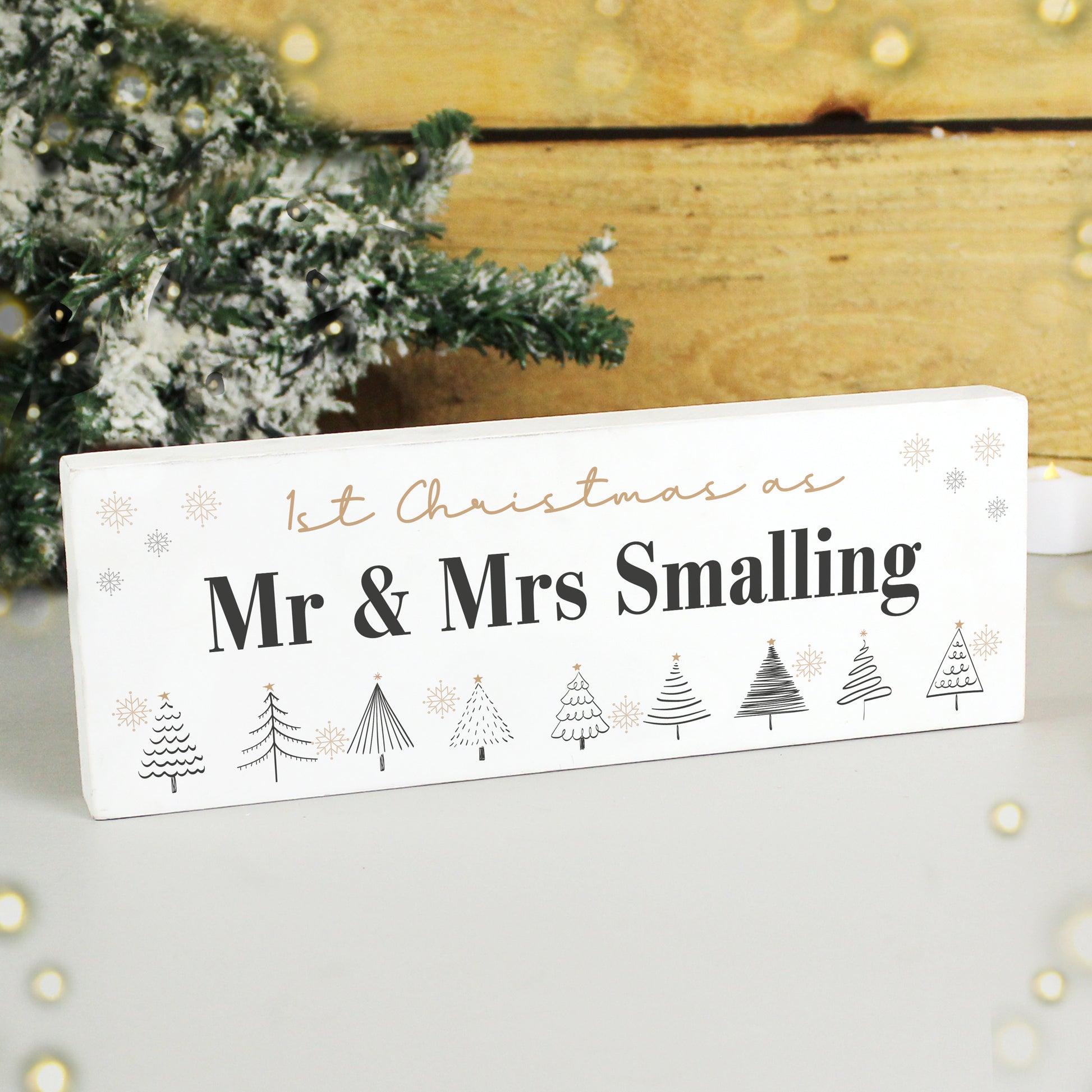 Personalised Christmas sign with tree designs and text in front of a decorated Christmas tree.