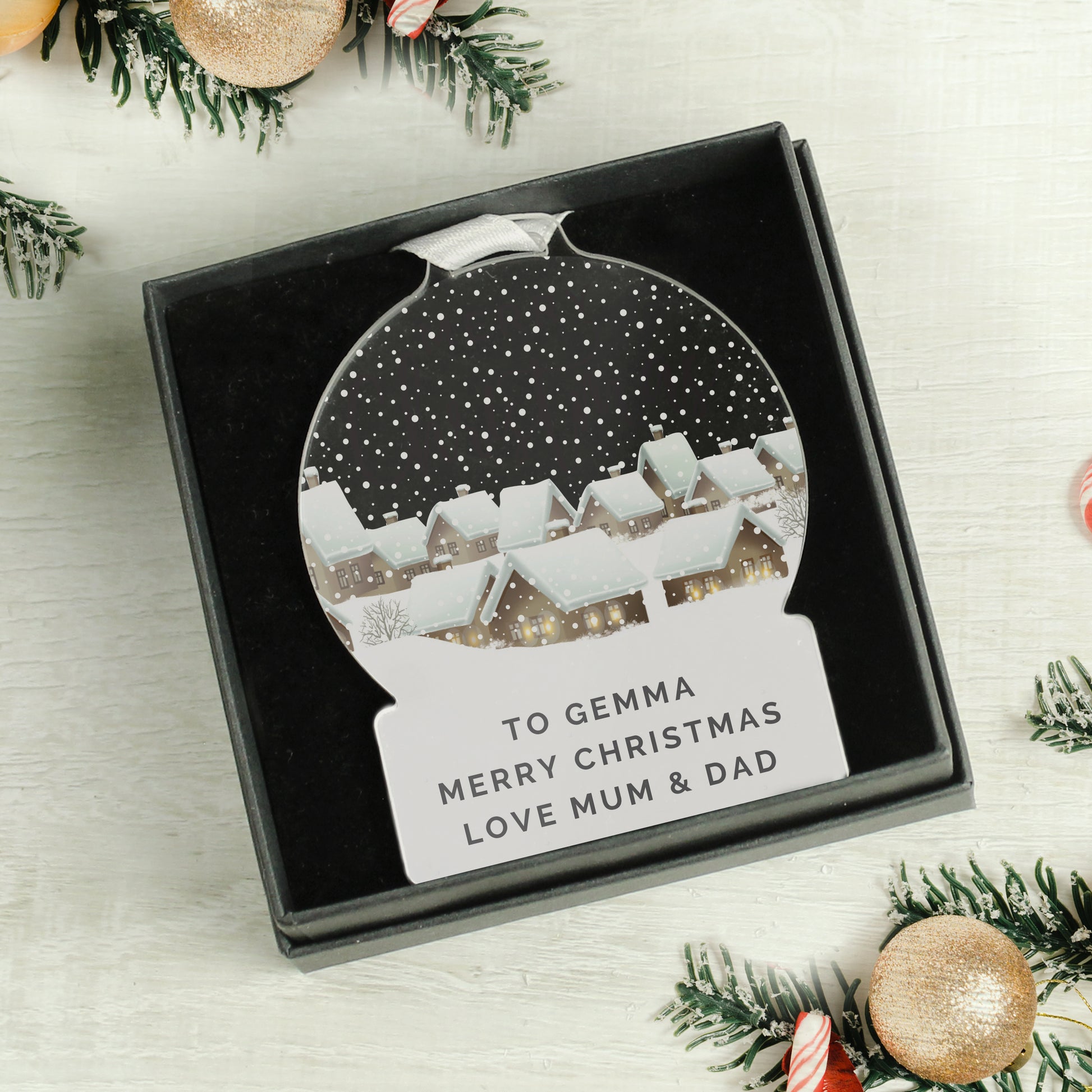 Personalized Christmas ornament in a box with festive decorations around