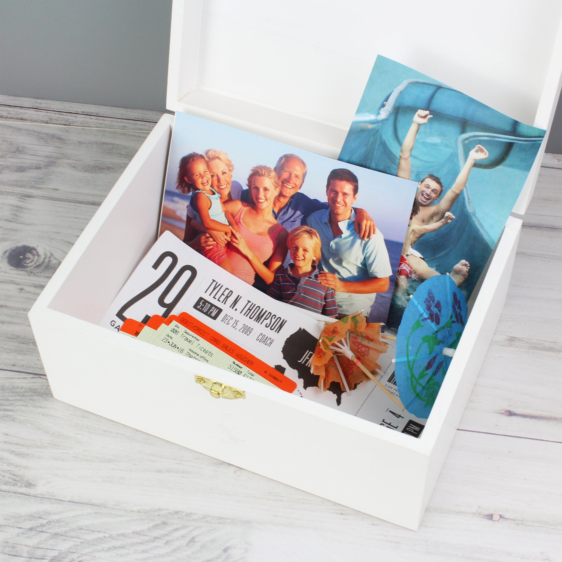 White box with a photo album and family photos on a wooden surface