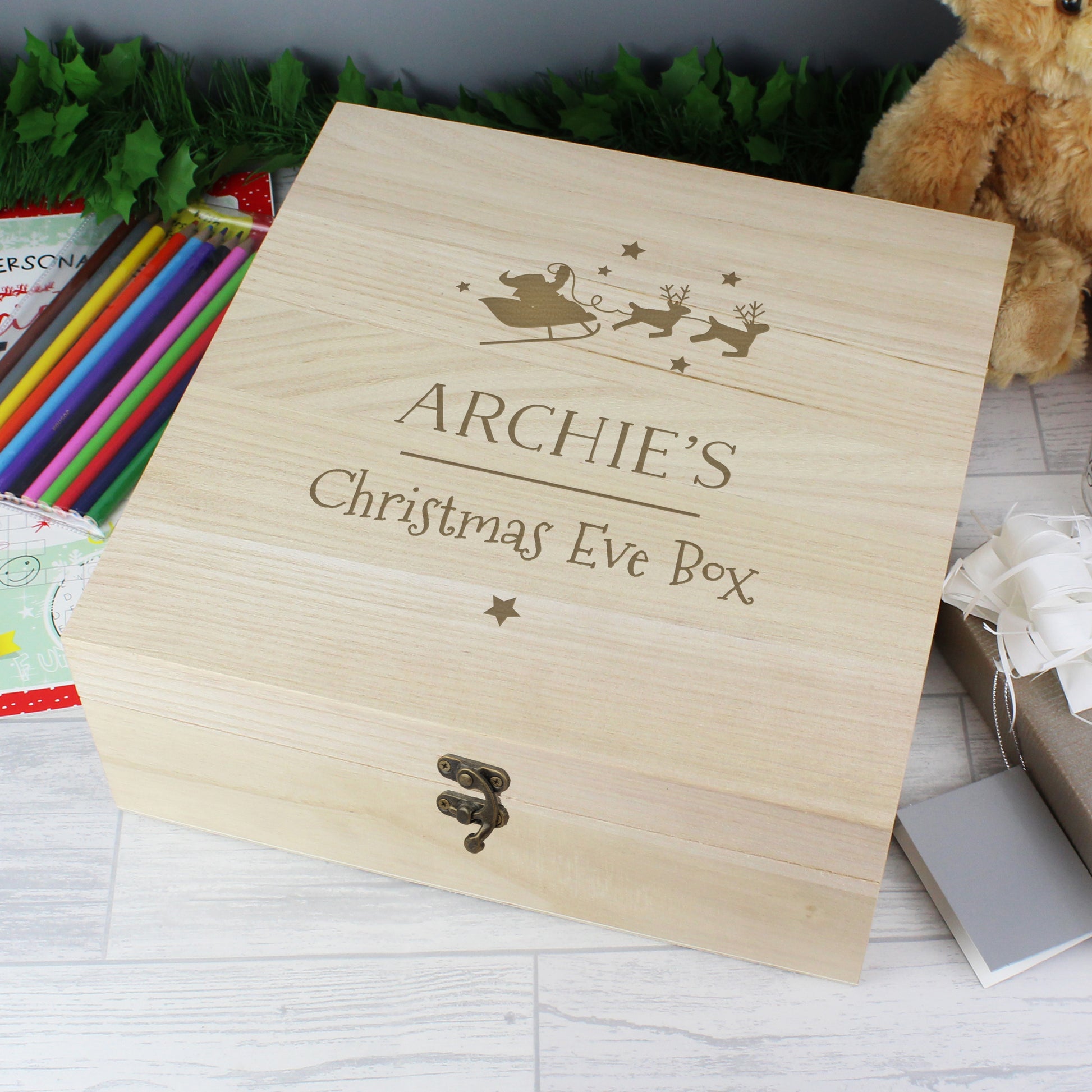 Wooden Christmas Eve box with 'Archie's' engraving on a festive background.