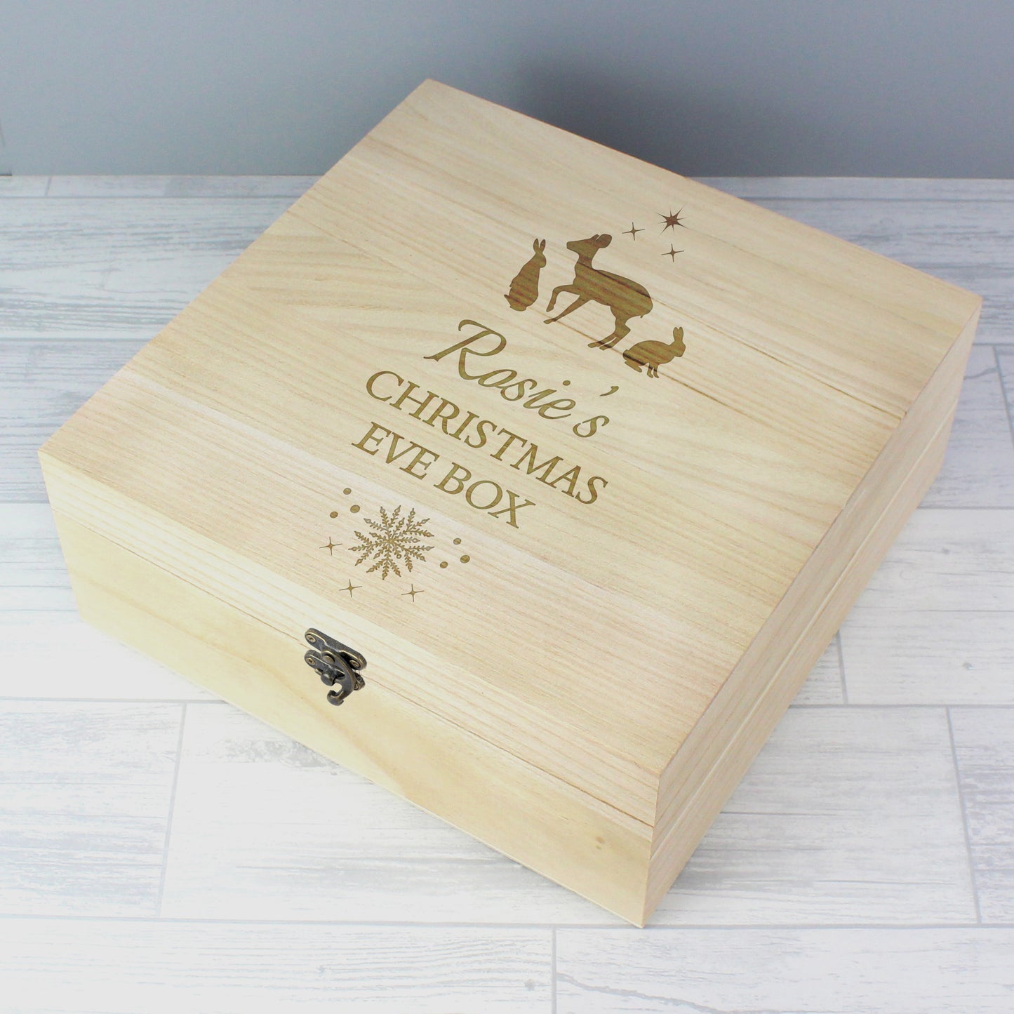 Wooden Christmas Eve box with engraved text and illustrations on a light wooden surface.