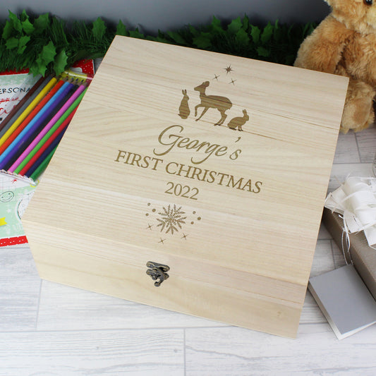 Wooden box with 'George's First Christmas 2022' engraving on a white surface with festive items.