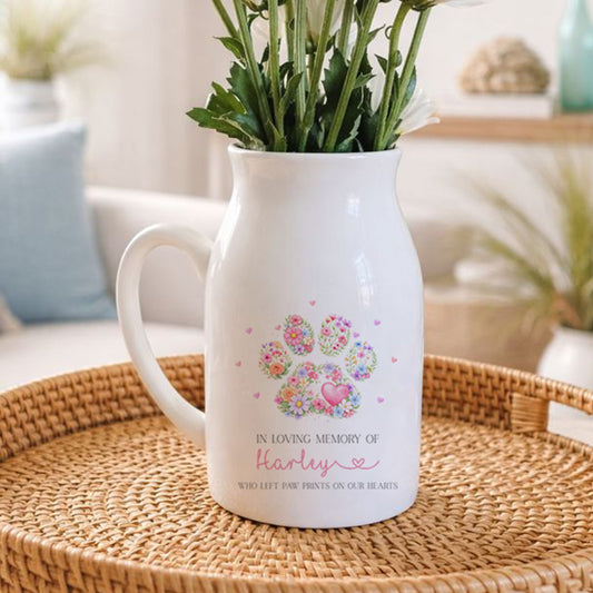White pet memorial pitcher with floral design on a woven tray in a living room setting