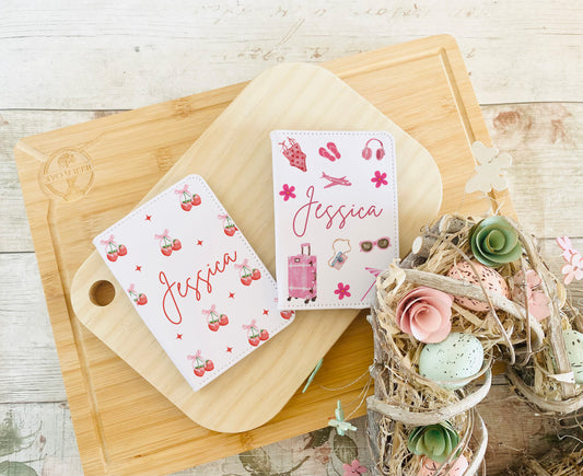 Custom name white passport holders in two designs: strawberry print and pink travel essentials, ideal for kids or girls' travel gifts