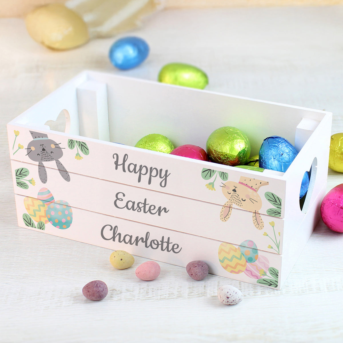 Easter basket with colorful eggs and personalized 'Happy Easter' sign on a light background