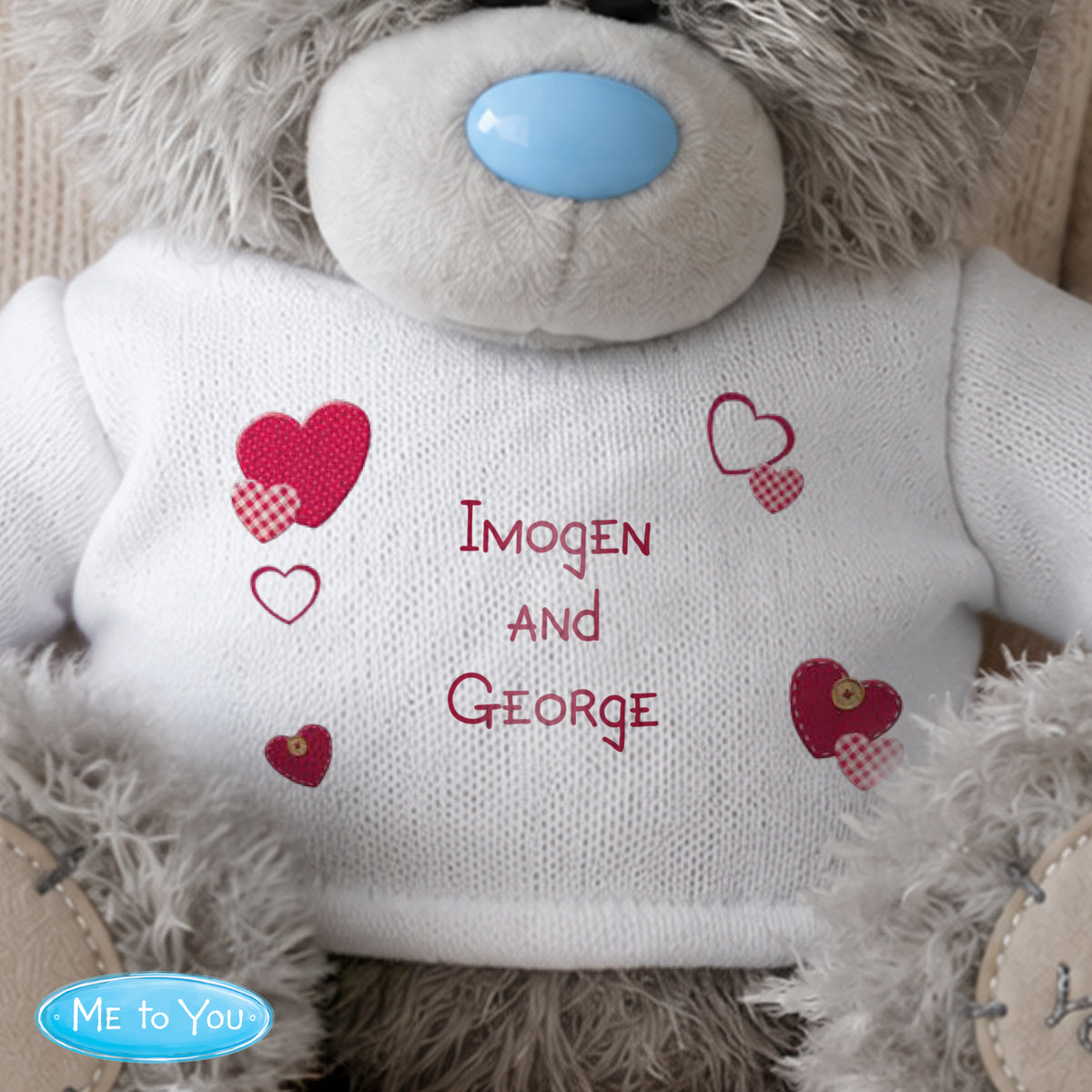 Personalised Teddy bear with 'Imogen and George' on its white shirt, featuring red hearts.