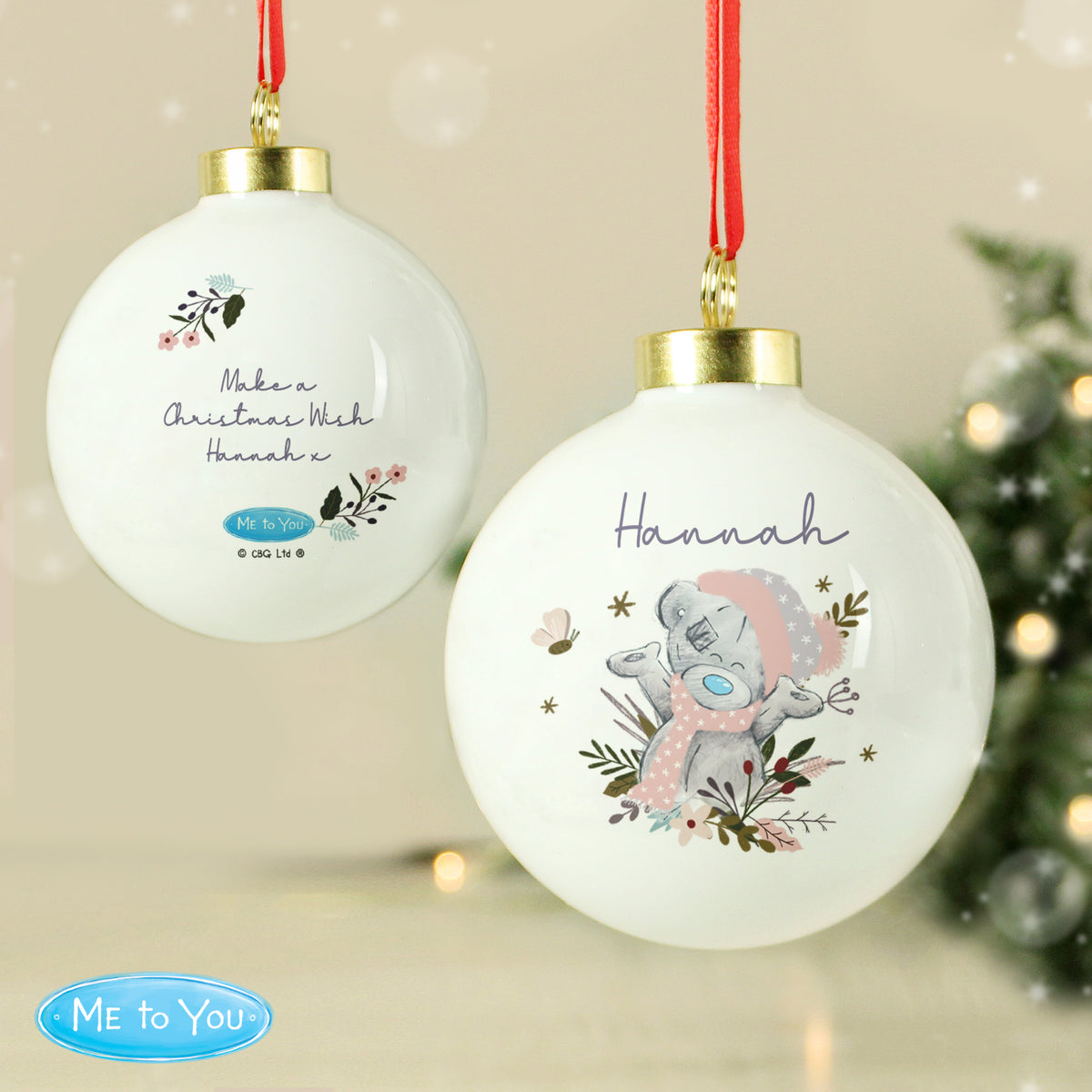 Personalised Christmas ornaments with a bear design and text, hanging against a festive background.