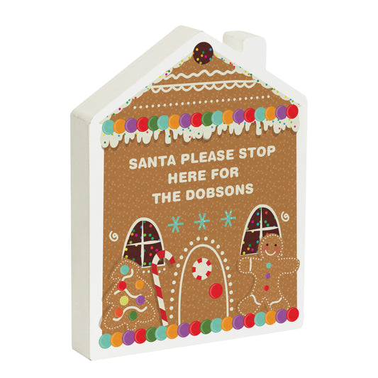 Personalised gingerbread house Christmas decoration with text "Santa please stop here for the Dobsons" – features candy details, gingerbread man, and festive tree, ideal for custom family names.