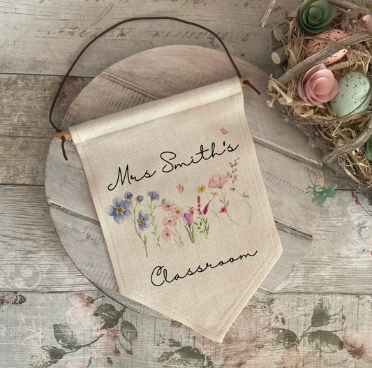 Decorative classroom teacher banner with floral design and text on a wooden surface