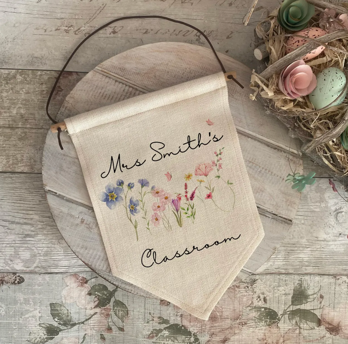 Decorative classroom teacher banner with floral design and text on a wooden surface