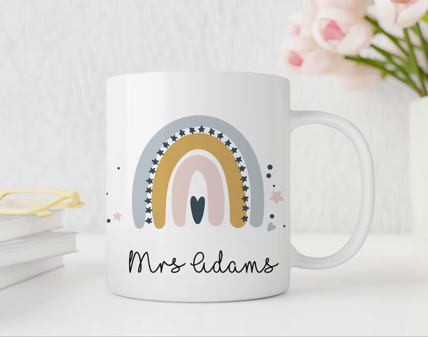 White mug with a rainbow design and 'Mrs Adams' text on a light background