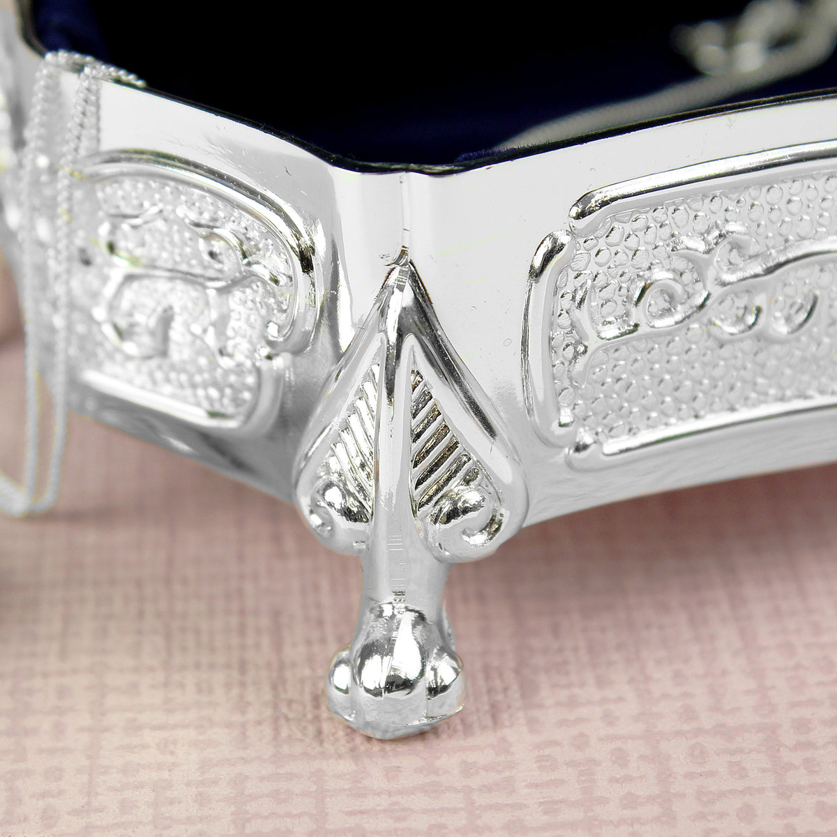Close-up of a silver bracelet with intricate designs on a pink fabric background
