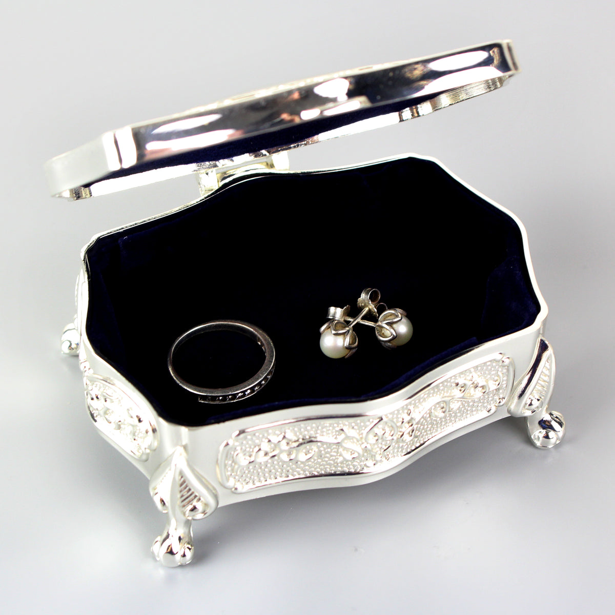Silver jewellery box with a black interior containing a ring and earrings on a light grey background