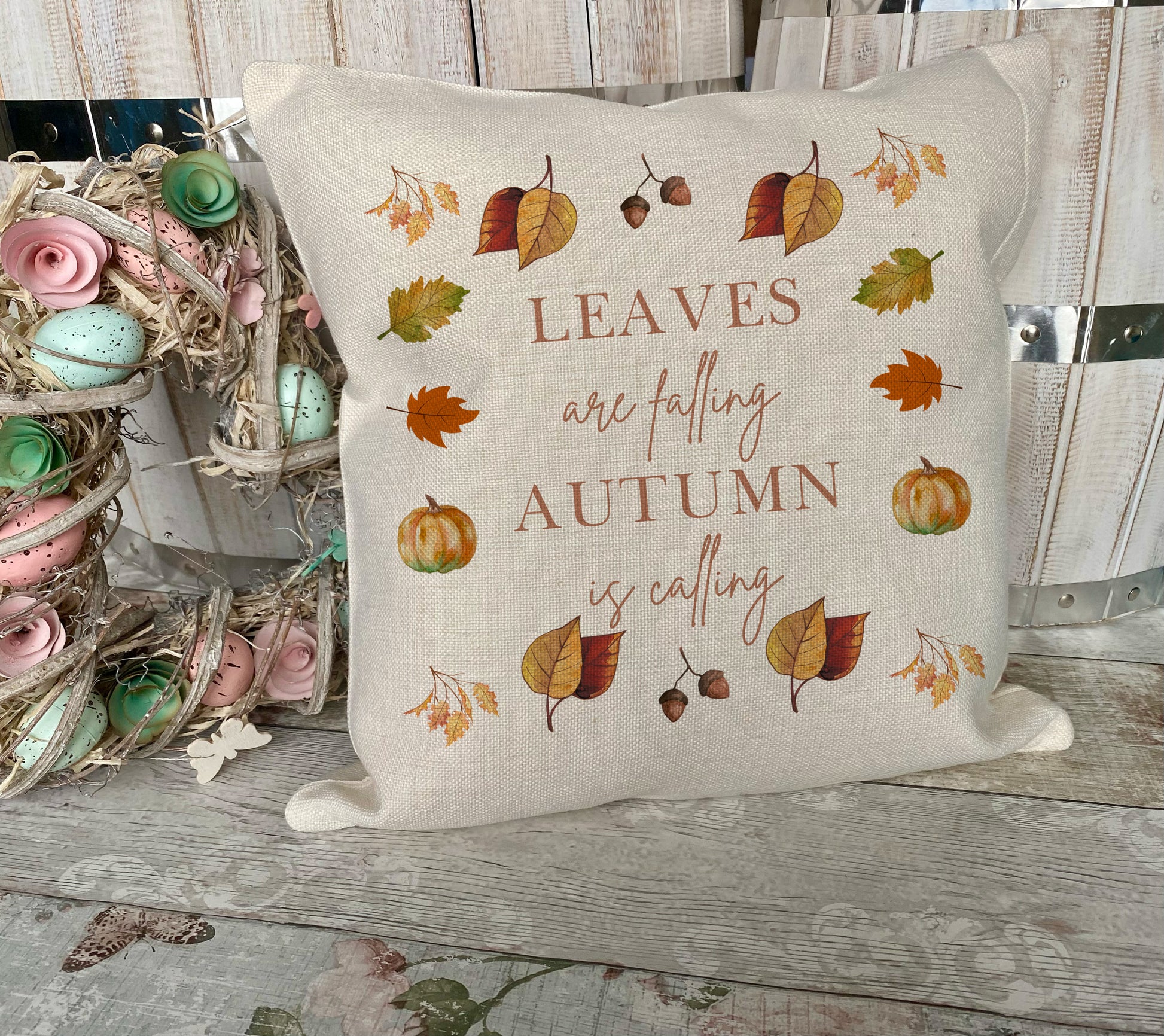 Decorative pillow with autumn-themed text and illustrations on a wooden surface.