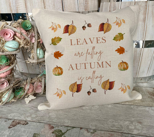Decorative pillow with autumn-themed text and illustrations on a wooden surface.