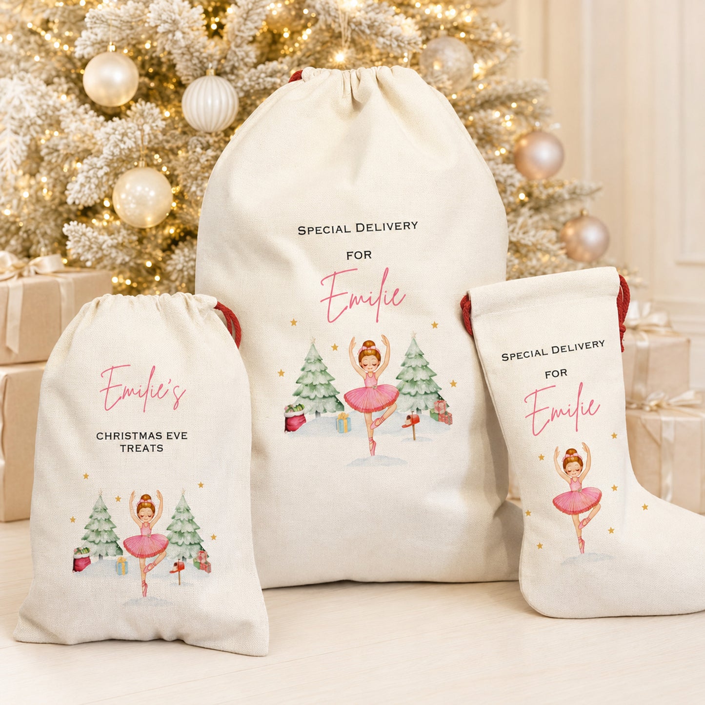 Three personalized cream canvas drawstring gift bags and a matching Christmas Eve stocking for Emily, decorated with a ballerina illustration and gold accents, displayed in front of a decorated Christmas tree.