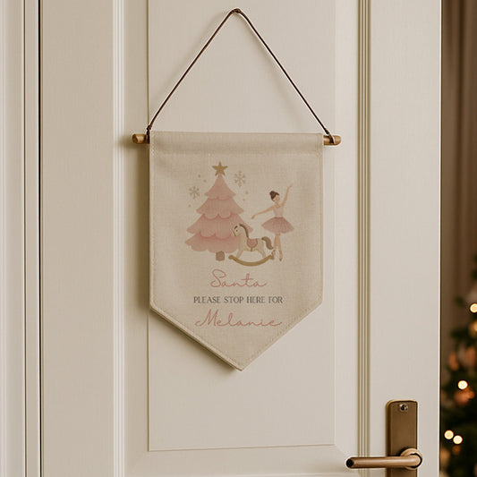 Decorative banner hanging on a white door with a Christmas tree in the background