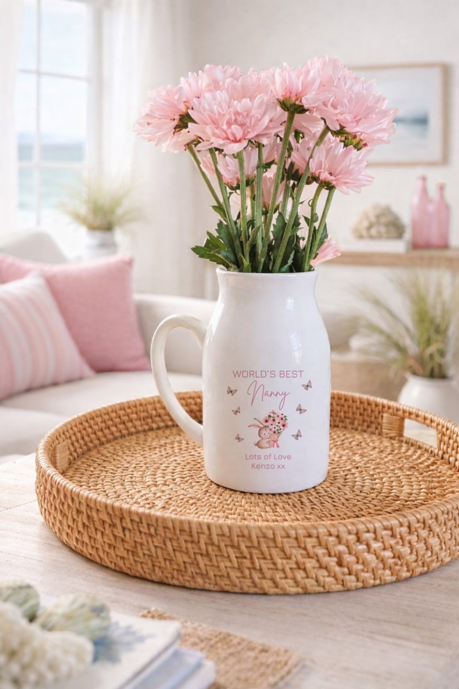 White pitcher featuring World's Best Nanny with pink flowers on a woven tray in a cozy living room