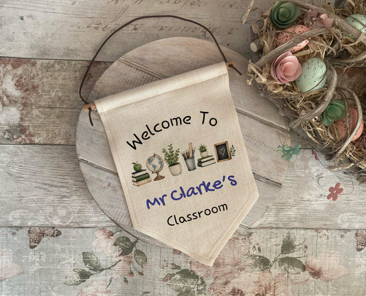 Decorative banner with 'Welcome to Mr Clarke's Classroom' text on a wooden surface with decorative elements.
