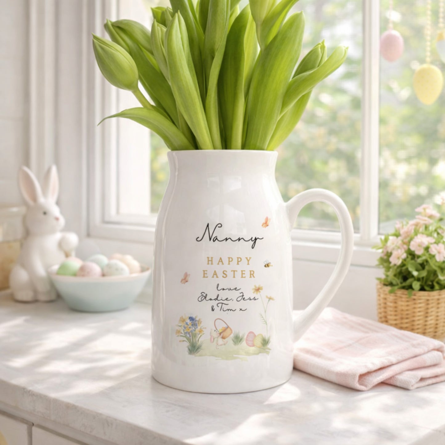 White personalised Easter Vase with 'Happy Easter' text and tulips on a table with Easter decorations.