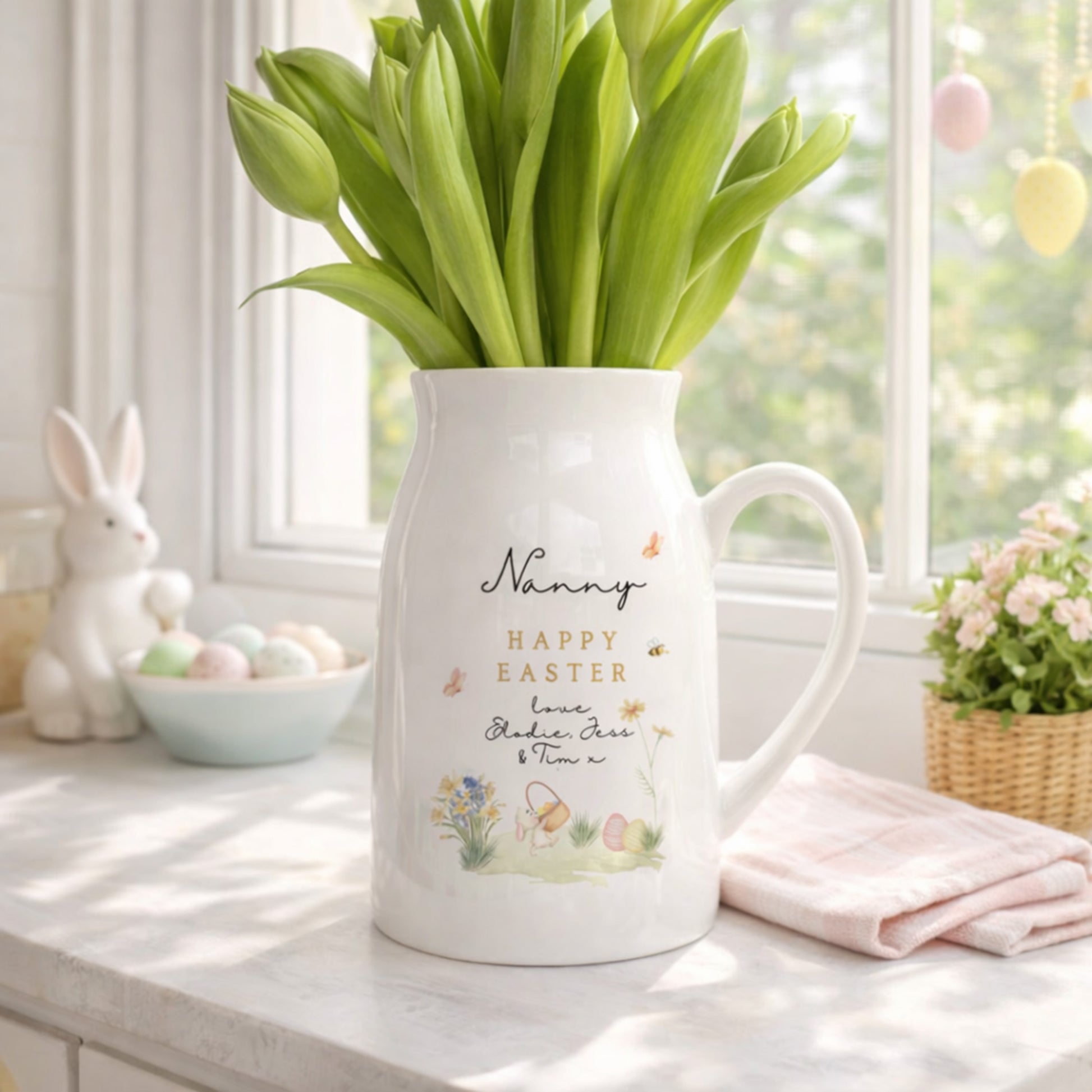 White personalised Easter Vase with 'Happy Easter' text and tulips on a table with Easter decorations.
