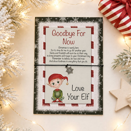 A Christmas-themed farewell card for an elf,  and displayed on a light beige surface with festive props including tinsel, fairy lights, a wrapped gift, and a wooden star.
