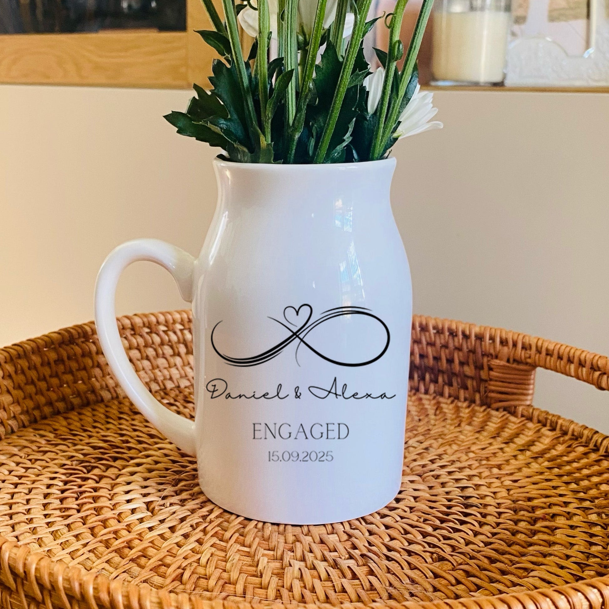 Personalised Engagement Vase, White pitcher with 'Engaged' text and an infinity sign, on a woven tray with flowers