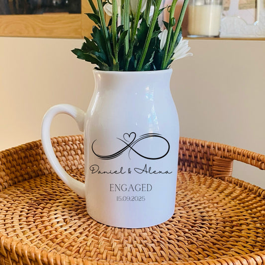 Personalised Engagement Vase, White pitcher with 'Engaged' text and an infinity sign, on a woven tray with flowers