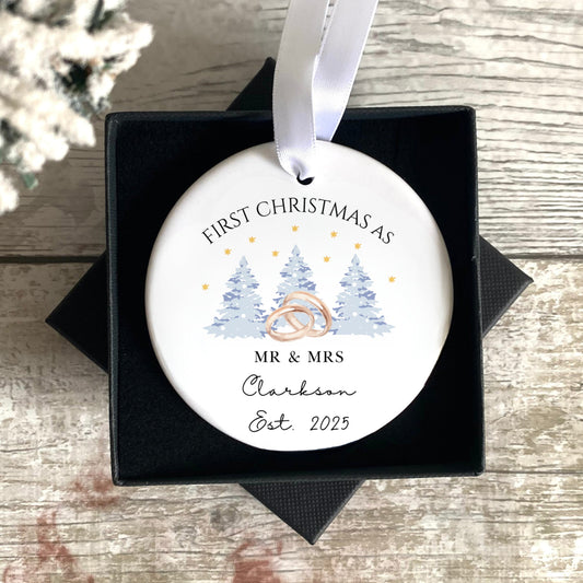 Personalised Christmas ornament in a black box on a wooden surface with a snowy background.