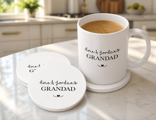 White mug and coasters with 'Evie & Jordan's Grandad' text on a kitchen counter.