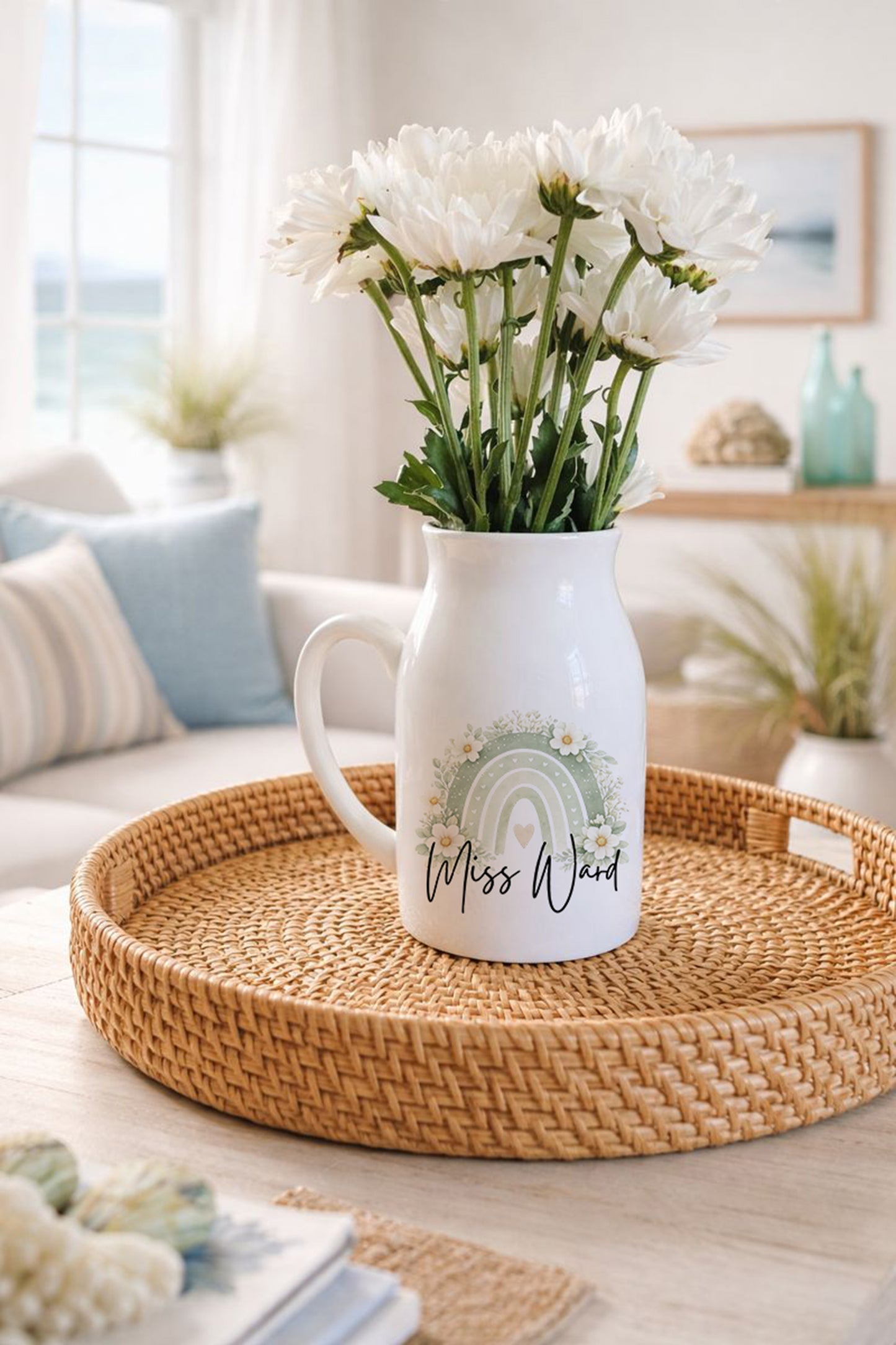 White pitcher with floral arrangement on a woven tray in a cozy living room.