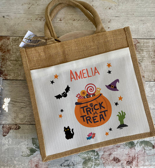 Halloween-themed tote bag with 'Trick or Treat' design and name 'Amelia' on a wooden surface.