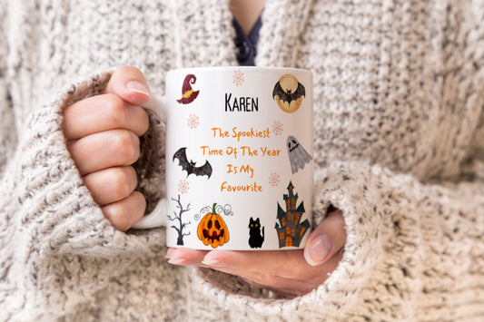 Person holding a Halloween-themed mug with decorative elements and text.