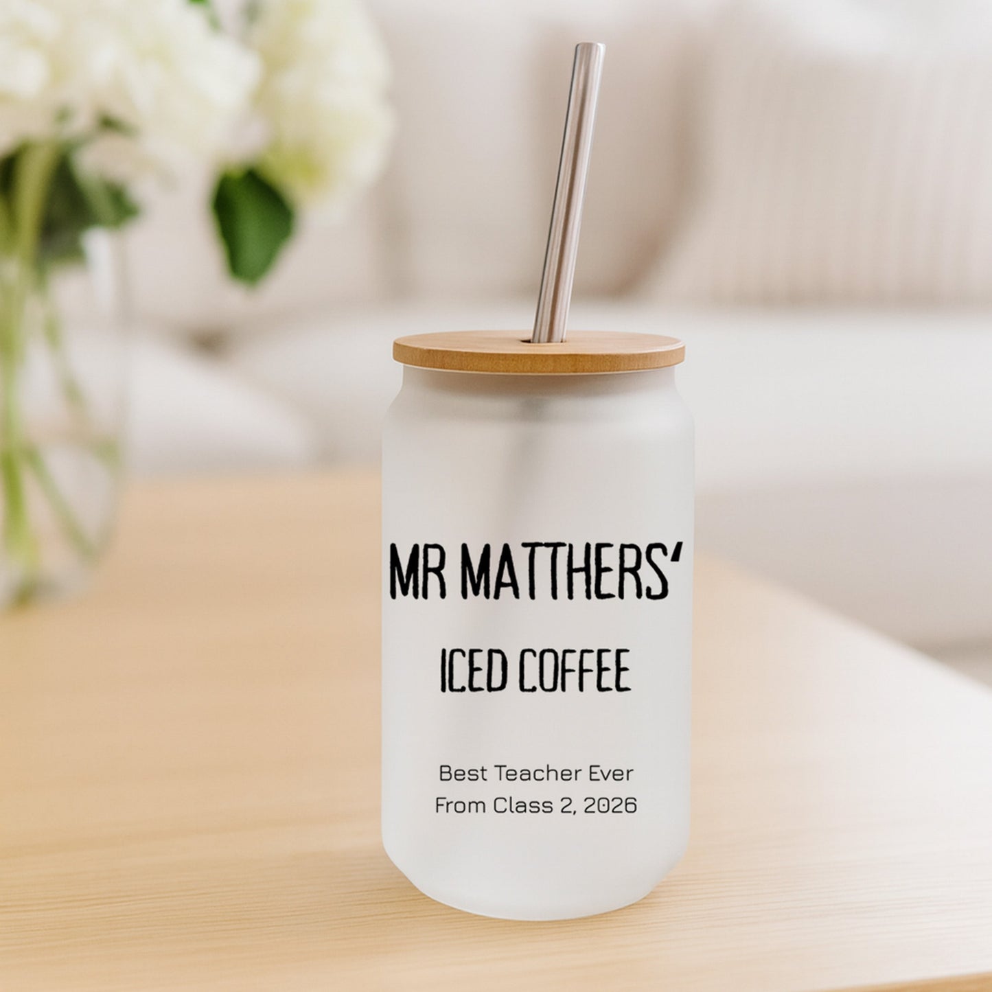 Personalized iced coffee tumbler with wooden lid and straw on a table.